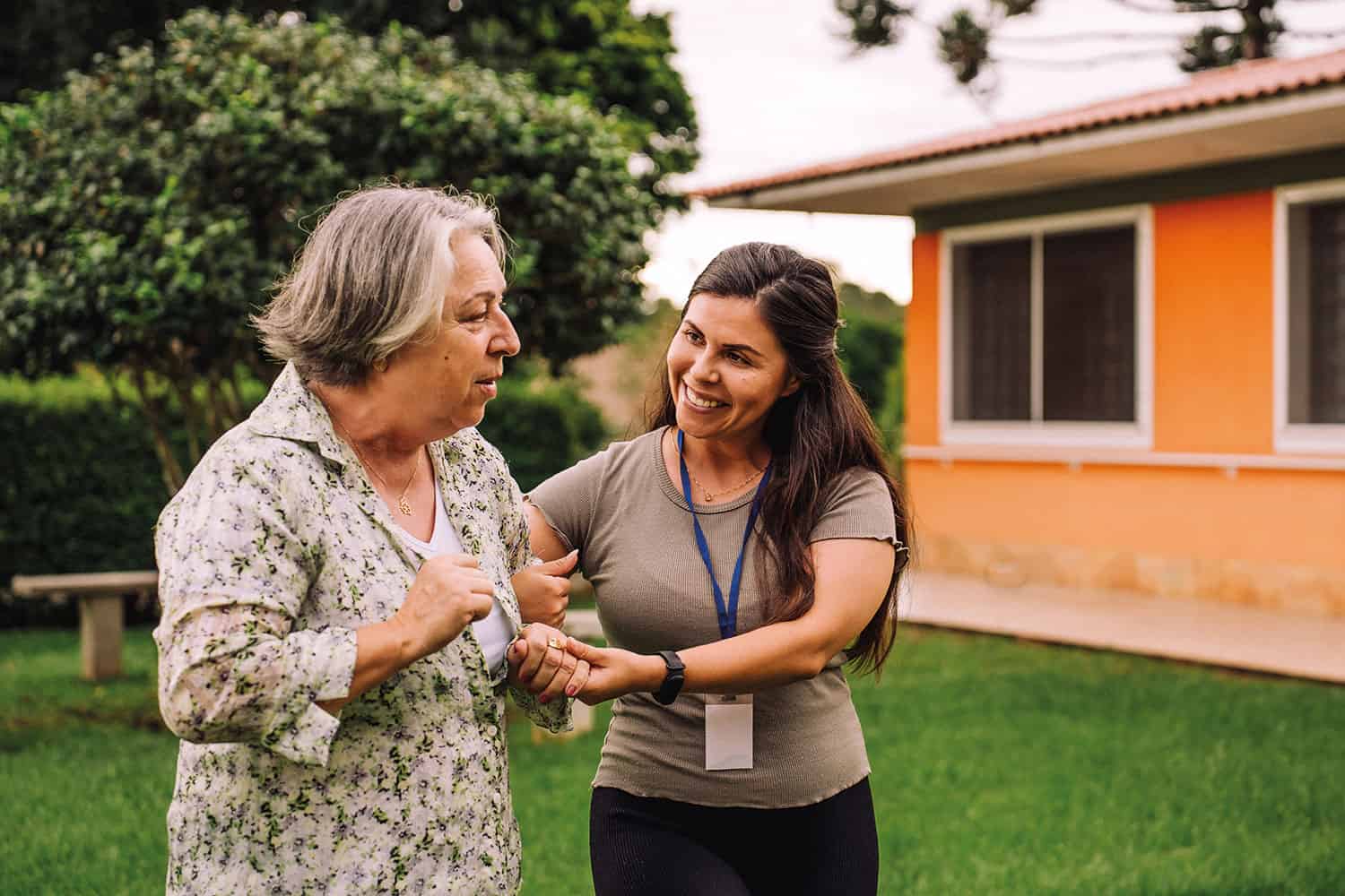 older woman arm-in-arm outdoors with younger female carer
