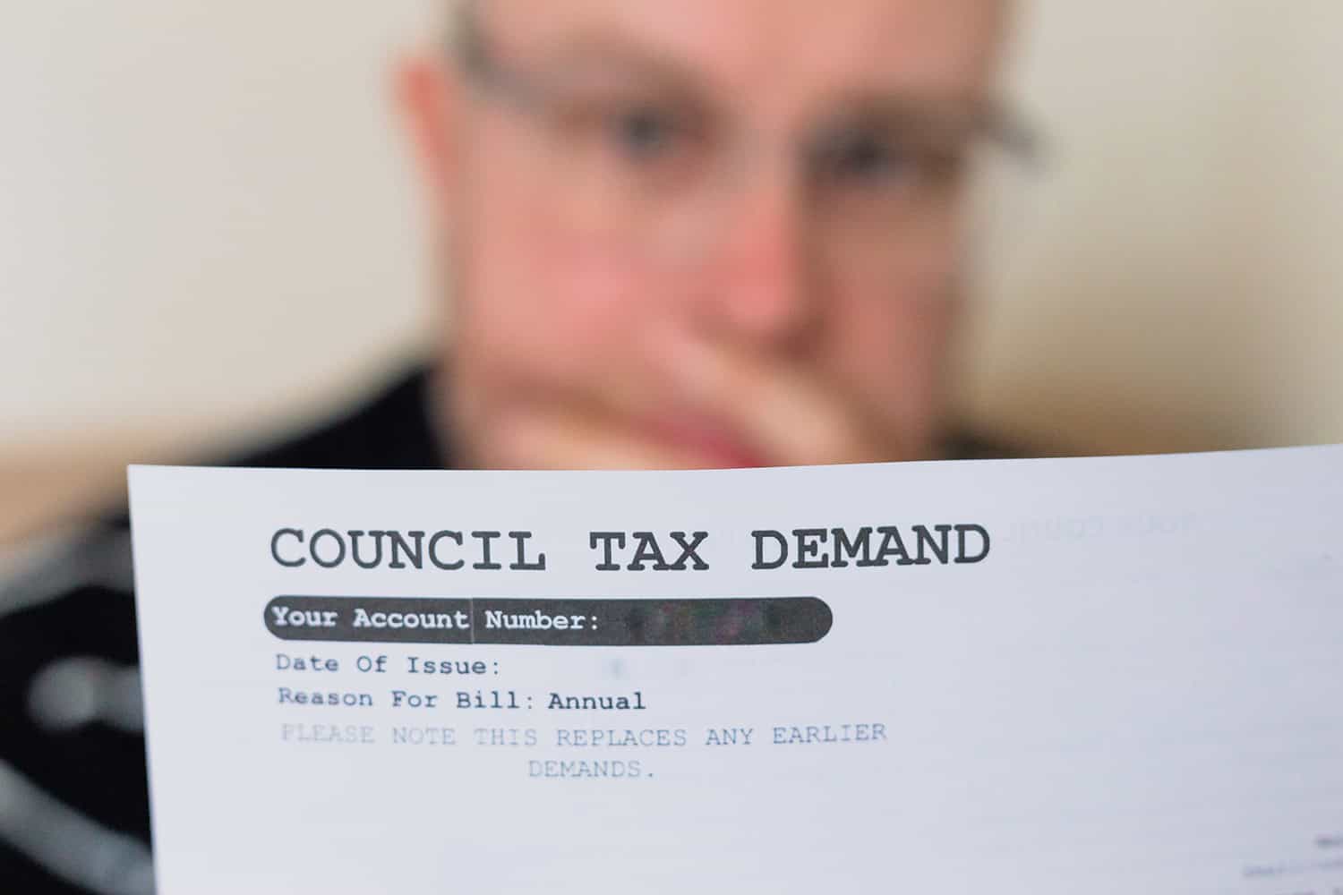 photo of an older man reading a council tax demand, focus on the letter
